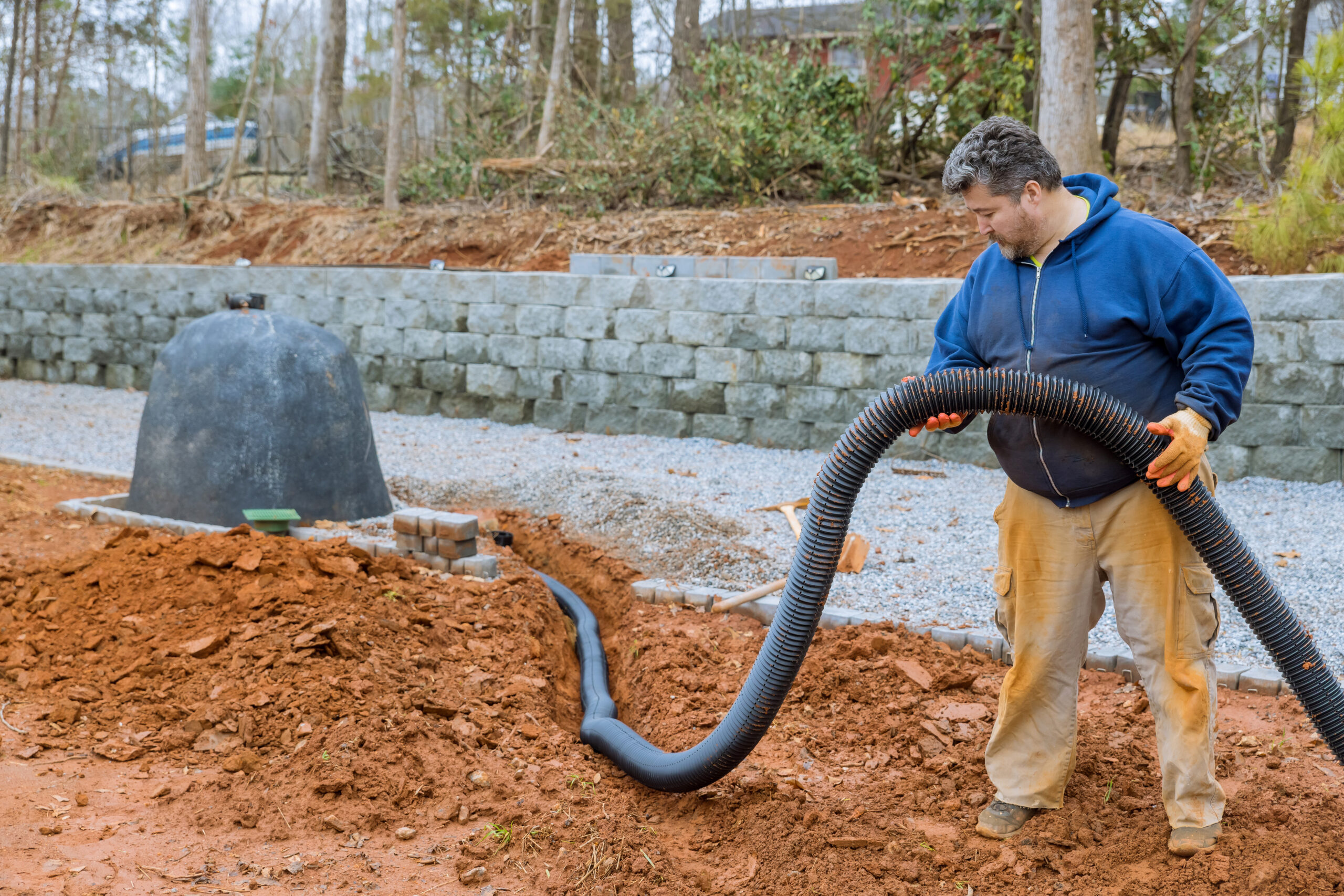 Putting down drainage pipes for rainwater on parking lot which is covered with gravel has driveway